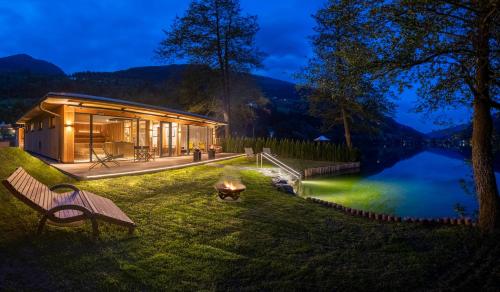 a house on the shore of a lake at night at Familien- Sportresort BRENNSEEHOF in Feld am See