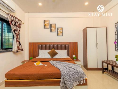 a bedroom with a bed with a wooden headboard at Staymist - Casa Palais in Lonavala