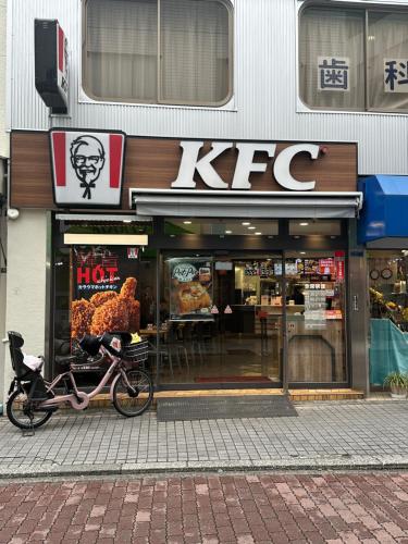 a bike parked in front of a kfc store at 5mins walk to Kameari Station within 30mins to Ginza, Asakusa, Skytree Direct bus to Haneda Airport & Tokyo Disneyland departing from Kameari Station in Tokyo