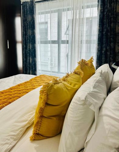 a yellow pillow on a bed with a window at StayEase 3BR apartment with Pool Spa & Gym in Johannesburg