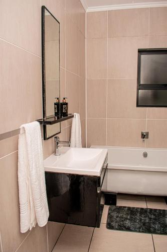 a bathroom with a sink and a mirror and a tub at StayEase 3BR apartment with Pool Spa & Gym in Johannesburg