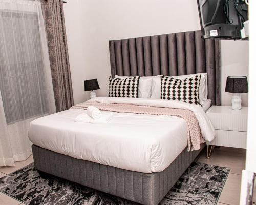 a bedroom with a large bed with a gray headboard at StayEase 3BR apartment with Pool Spa & Gym in Johannesburg