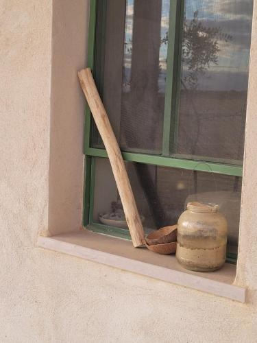 a window sill with a wooden cross and a jar at בקתה וטבילה במדבר in H̱aẕeva