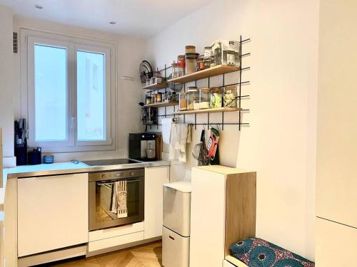 une cuisine avec des armoires blanches et une fenêtre dans l'établissement Charmant appartement calme 2 personnes, à Paris