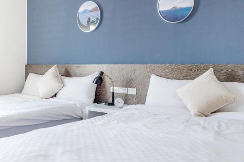 two beds in a bedroom with two mirrors on the wall at Penghu Sea Residences Hall in Magong