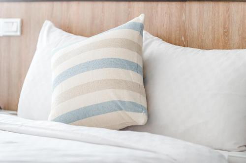 a bed with white pillows and a striped pillow at Penghu Sea Residences Hall in Magong