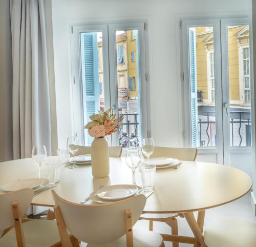 une salle à manger blanche avec une table et des chaises blanches dans l'établissement République Appartements, à Menton