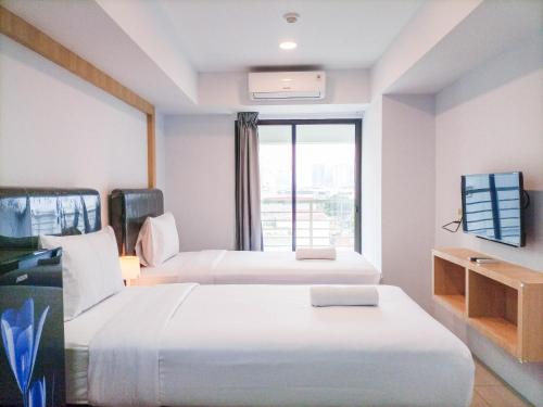 a hotel room with two beds and a window at Luxurious Studio at De Prima Apartment By Travelio in Medan