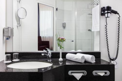 y baño con lavabo y espejo. en IntercityHotel Freiburg en Friburgo de Brisgovia