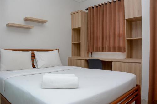 una camera da letto con un letto bianco e una scrivania di Homey and Cozy Living 1BR Apartment at Atlanta Residences By Travelio a Depok