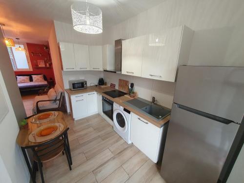 une cuisine avec un réfrigérateur, un évier et une table dans l'établissement studio cosy idéalement situé parking privé, à Ajaccio