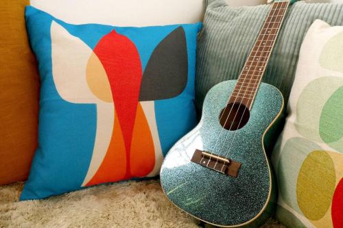 a guitar sitting on a couch next to a pillow at プライベート天然温泉 - 広々清潔 - 素敵な非日常! Private Hot Spring - Spotless Modern Japanese in Ito