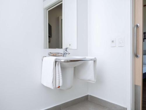 a white bathroom with a sink and a mirror at ibis budget Sorocaba in Sorocaba