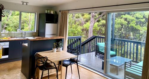 a kitchen with a balcony with a table and chairs at Cosy Bush Apartment in Auckland