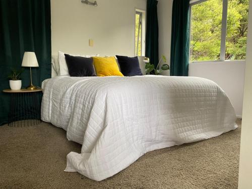 a bed with a white comforter and pillows at Cosy Bush Apartment in Auckland