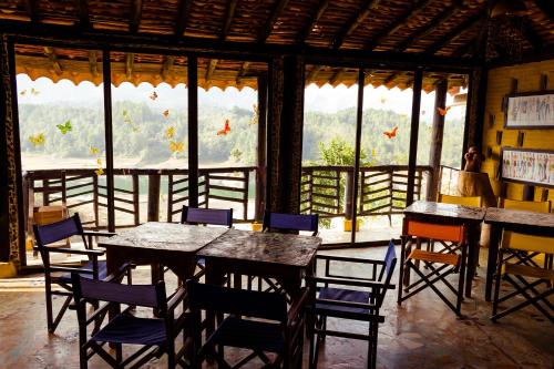 a dining room with tables and chairs and windows at Casa Encuentro Ecolodge, Outdoor Gym and Yoga in Guatapé
