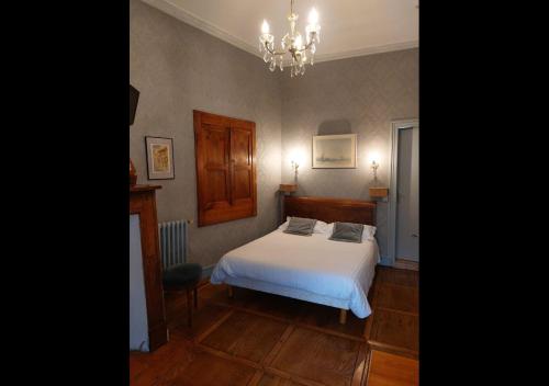 a bedroom with a white bed and a chandelier at Logis Hôtel Beau Site in Argelès-Gazost