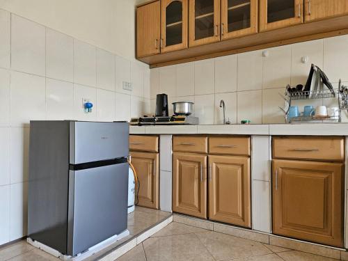 Una cocina con gabinetes de madera y un refrigerador de acero inoxidable. en NL residence - Kampala, en Kampala