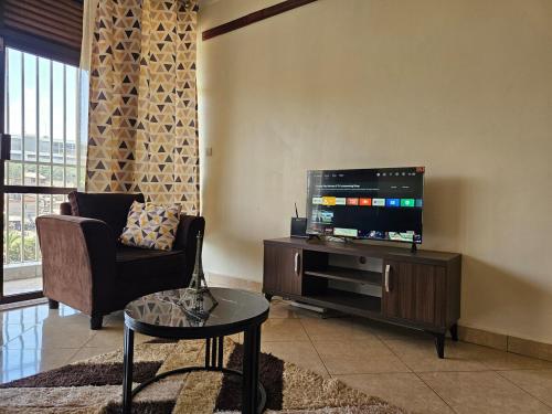 Una sala de estar con un televisor, un sofá y una mesa. en NL residence - Kampala, en Kampala