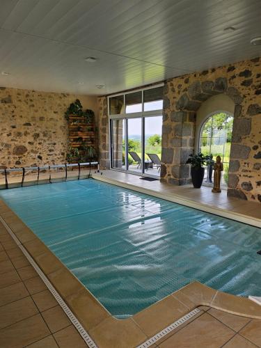 une piscine intérieure avec un mur en pierre dans l'établissement Au détour du Puy Maison avec piscine intérieure à 15 mn Puy du Fou, à Pouzauges