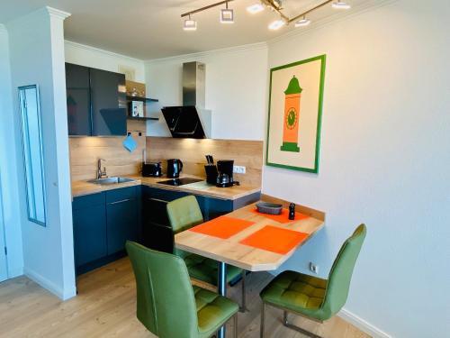 Una cocina con una mesa de madera y sillas verdes. en 307 im Lord Nelson, en Cuxhaven
