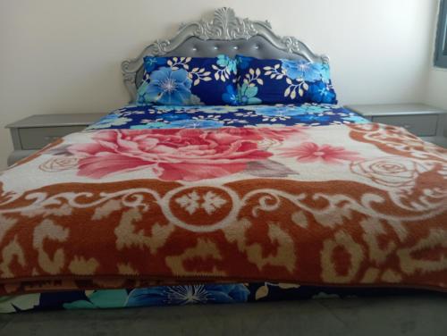 un letto con copriletto rosso e blu con fiori di Full apartment all is yours a Sharjah