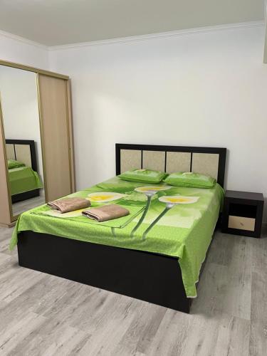 a bedroom with a bed with a green comforter and mirrors at Apartament27 in Almaty
