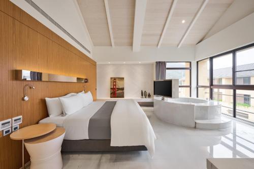 a bedroom with a large bed and a tub at The Westin Yilan Resort in Yuanshan