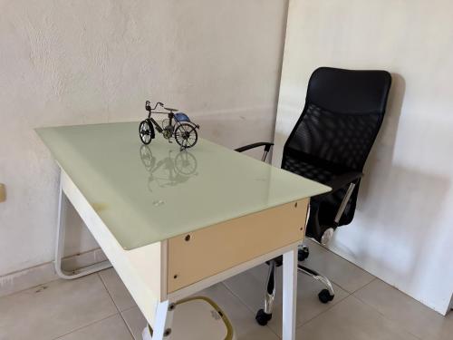 a white desk with a bike on it next to a chair at Casa La Perla del Sur Confort y calidez en todos sus espacios in Ticul