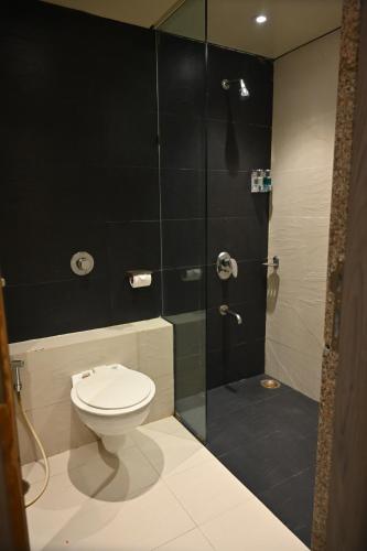 a bathroom with a toilet and a glass shower at Kumar Resort By Turtle, Lonavala in Lonavala