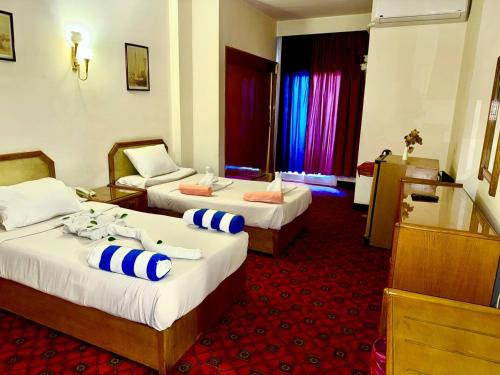 a hotel room with two beds and a chair at Queens Valley Hotel in Luxor