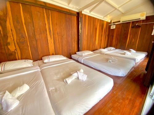 a row of beds in a room with wooden walls at The Sun House อุทัยธานี in Ban Nam Tok