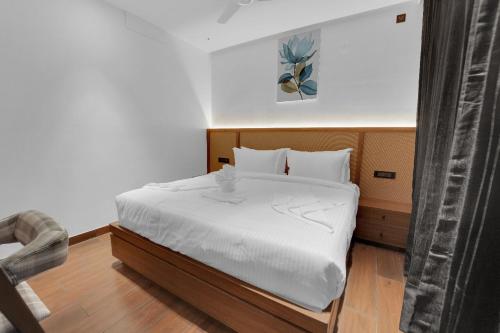 a small bedroom with a bed with white sheets at The Forest Glen by TIO Hotels in Yercaud