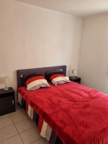 une chambre avec un lit rouge avec deux oreillers dans l'établissement Appartement Le Petit Nid Cévenol, à Anduze