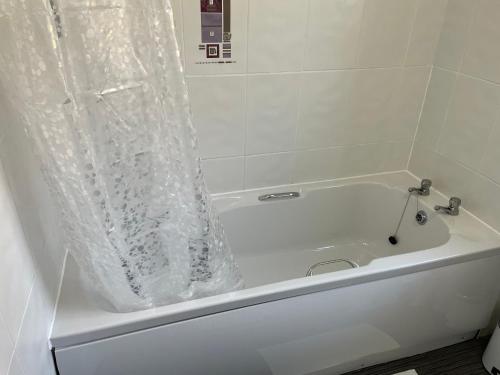 a white bath tub with a plastic shower curtain on it at Dumbarton With A View in Dumbarton