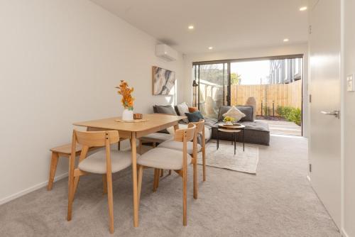 a dining room and living room with a table and chairs at Brand New Luxury 3 Bed 3 Baths Family Getaway in Christchurch