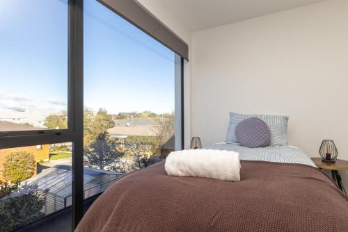 a bedroom with a bed and a large window at Brand New Luxury 3 Bed 3 Baths Family Getaway in Christchurch