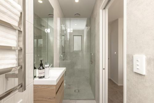 a bathroom with a shower and a sink with a glass shower stall at Brand New Luxury 3 Bed 3 Baths Family Getaway in Christchurch
