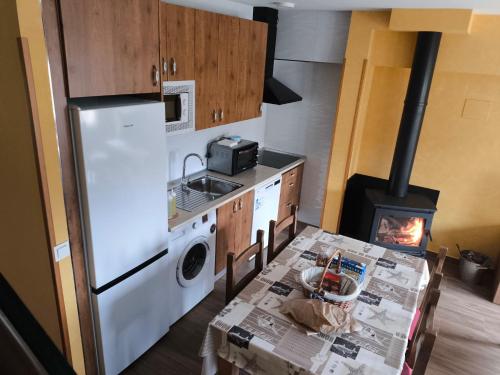 a kitchen with a refrigerator and a table with a stove at Granja Las Callejuelas in Casla