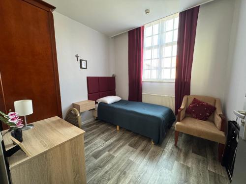 a small room with a bed and a chair at B&B Maria Hart in Weert