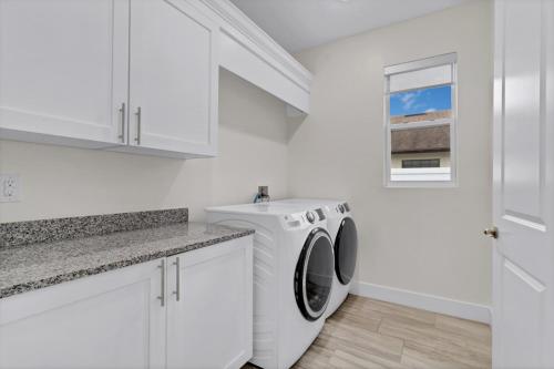 a white laundry room with a washer and a window at Sunny Stay Orlando Queen Room 3 with Shared Bath in Orlando