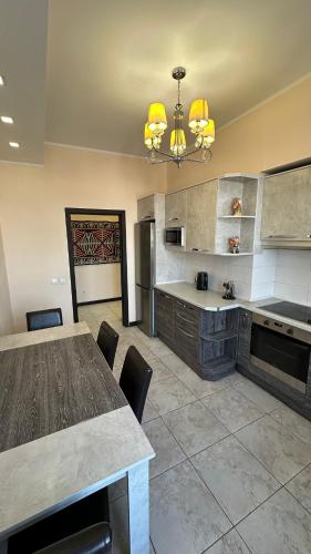 Una gran cocina con una mesa y sillas y una lámpara de araña. en Comfortable flat in center, en Bishkek