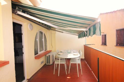 une table blanche et des chaises sur un balcon avec auvent dans l'établissement Le Poisson Bleu, à Collioure