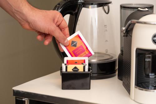 a person holding a box on a counter next to a coffee maker at Oidu - Cagliari Suites in Cagliari
