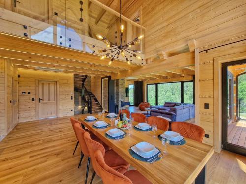 a dining room with a large wooden table and chairs at LK Forest Villa luksusowe domy z basenem z jacuzzi, sauną, grotą solną, salą bilardową i ogrodem in Łapsze Niżne