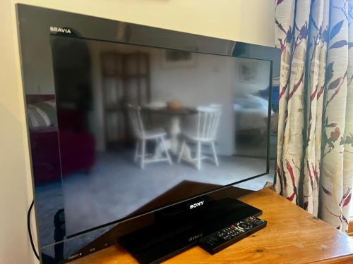 a flat screen tv sitting on a table with two remote controls at Self-contained Guest Suite, Michelmersh, Romsey in Michelmersh