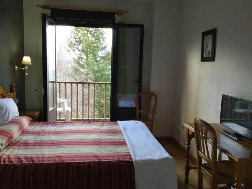 a bedroom with a bed and a window with a balcony at Hotel Cinco Castaños in Candelario
