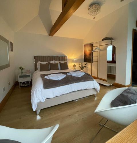 a bedroom with a large bed and a chair at Little Monks Suite in Offenham