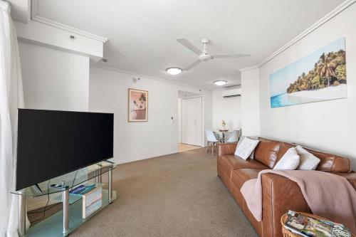 a living room with a couch and a flat screen tv at Inner City Gem - Stunning Views in Cairns