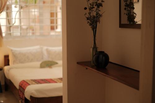 a bedroom with a bed and a vase with flowers on a table at Le Mékong Bleu in Ben Tre